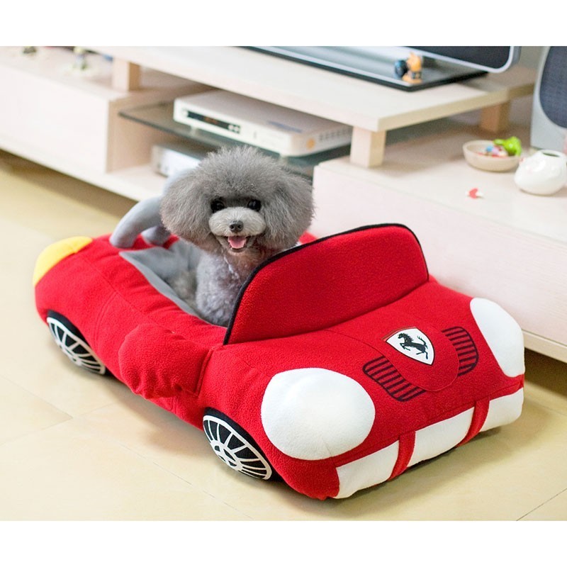 Golden puppy sitting in red car-shaped pet nest — soft plush dog and cat bed
